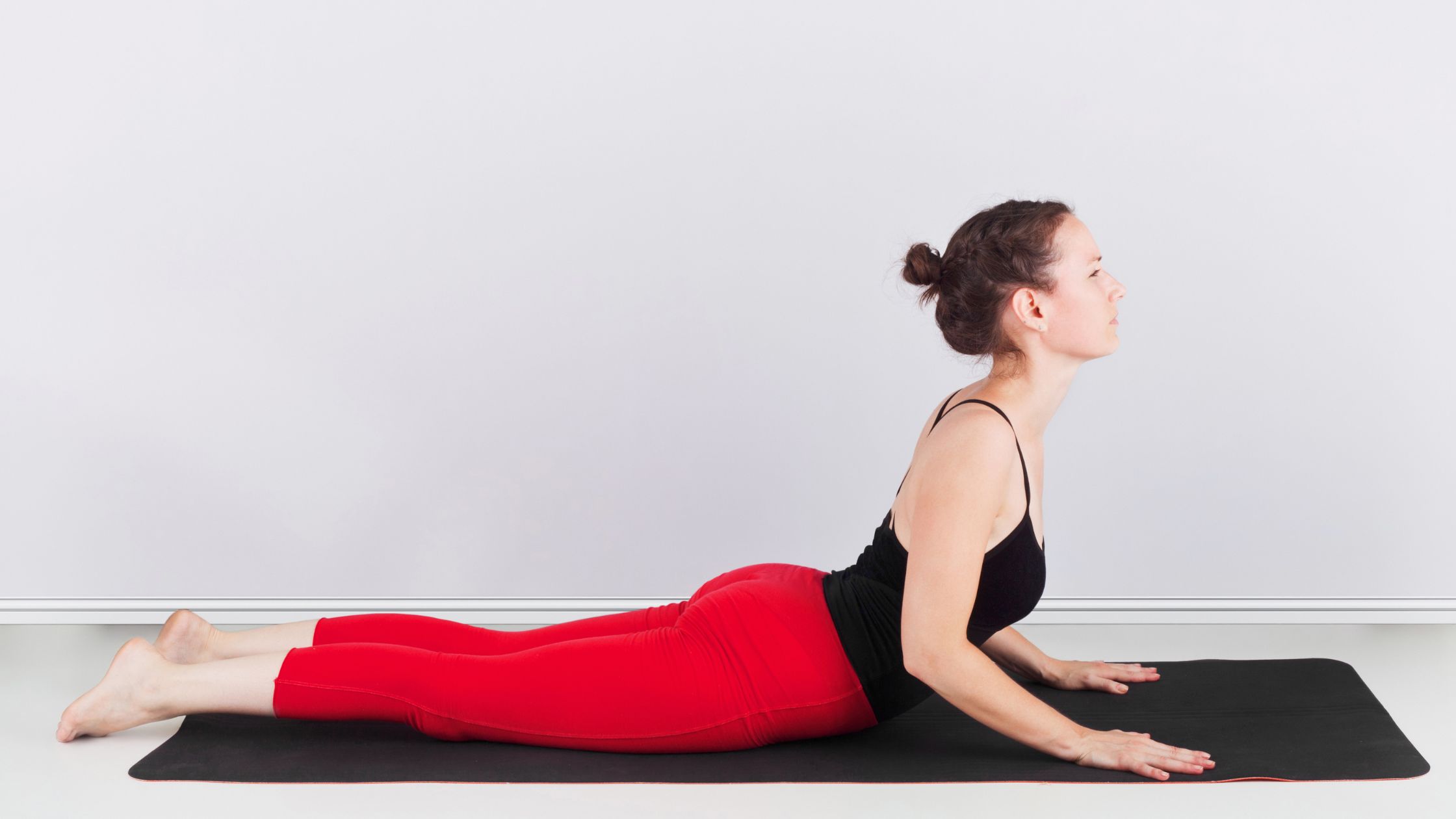 Femme avec hernie discale lombaire faisant un étirement du coude sur le ventre pour la thérapie physique.